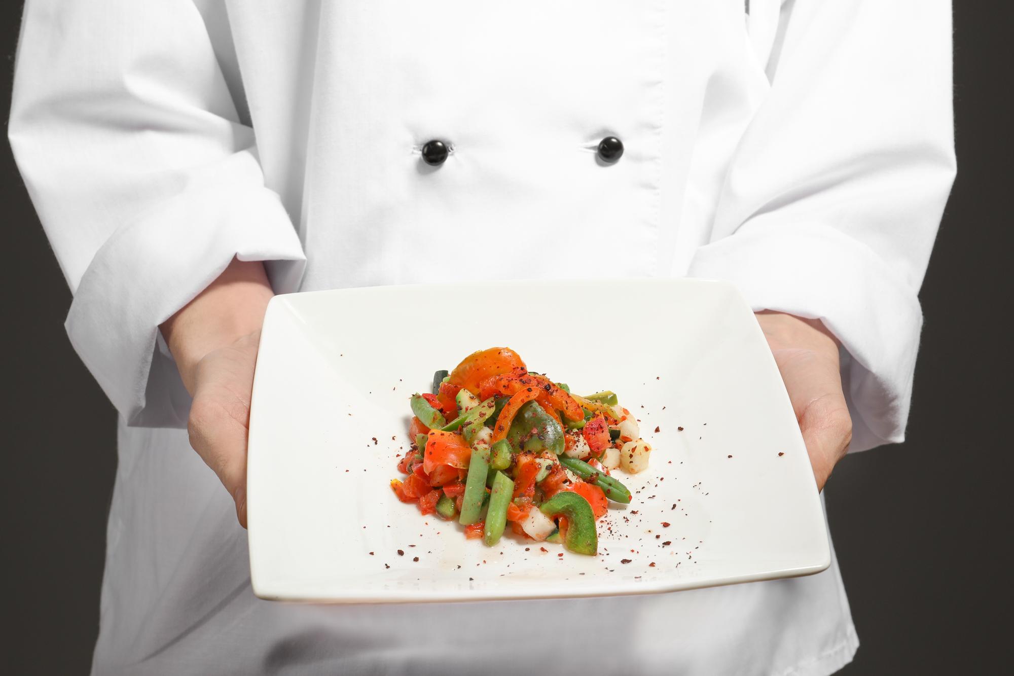 Chef arranging a simple plated dish on a wooden table